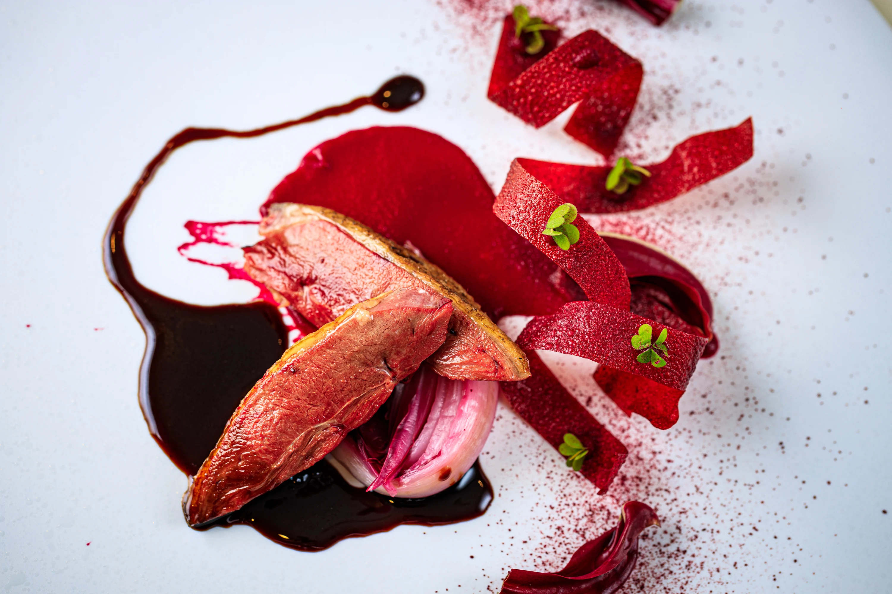 A sculptural red starter arranged with sauce and delicate garnishes.