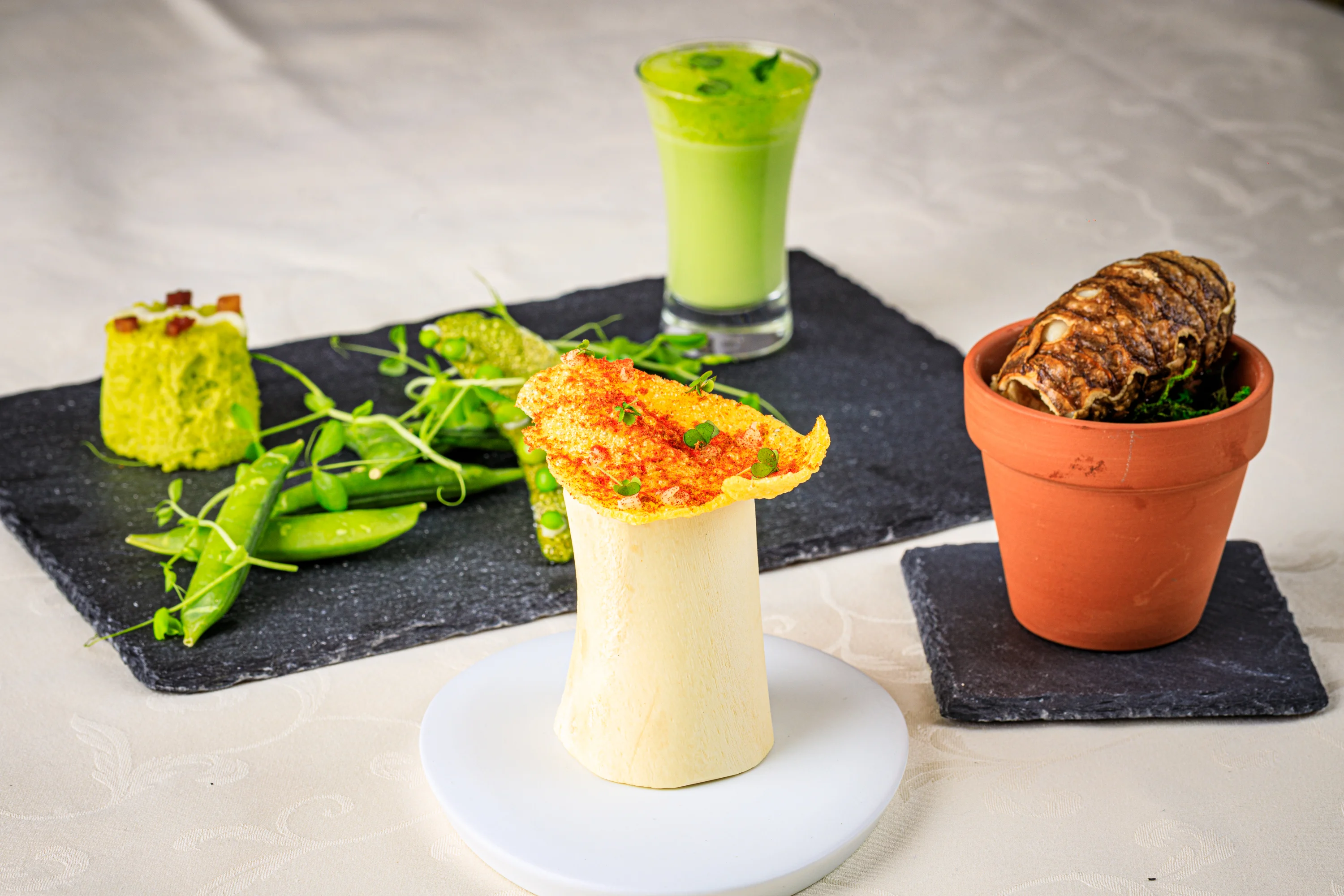 A playful tasting plate with small savory elements and green juice.