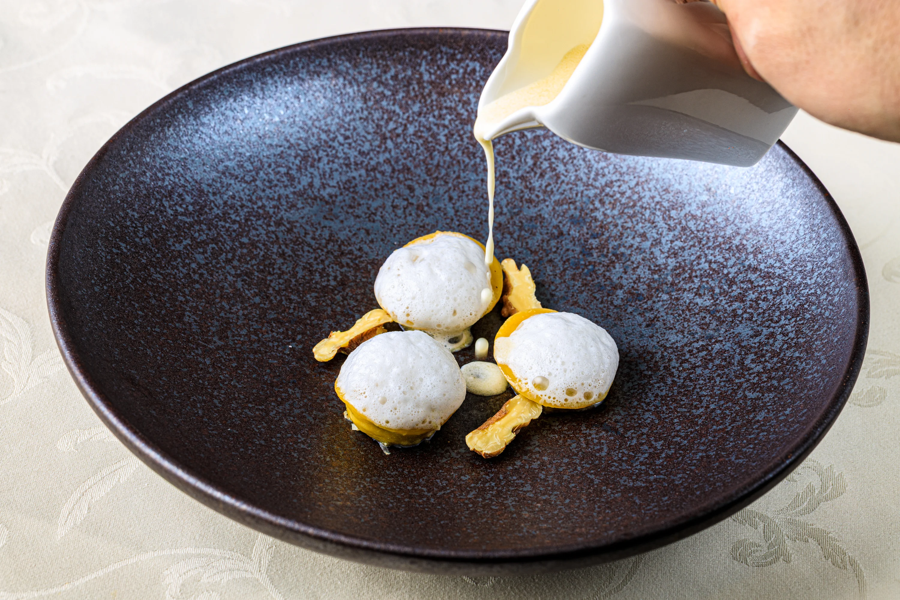 A glass dessert with red sauce, berries and delicate edible flowers.