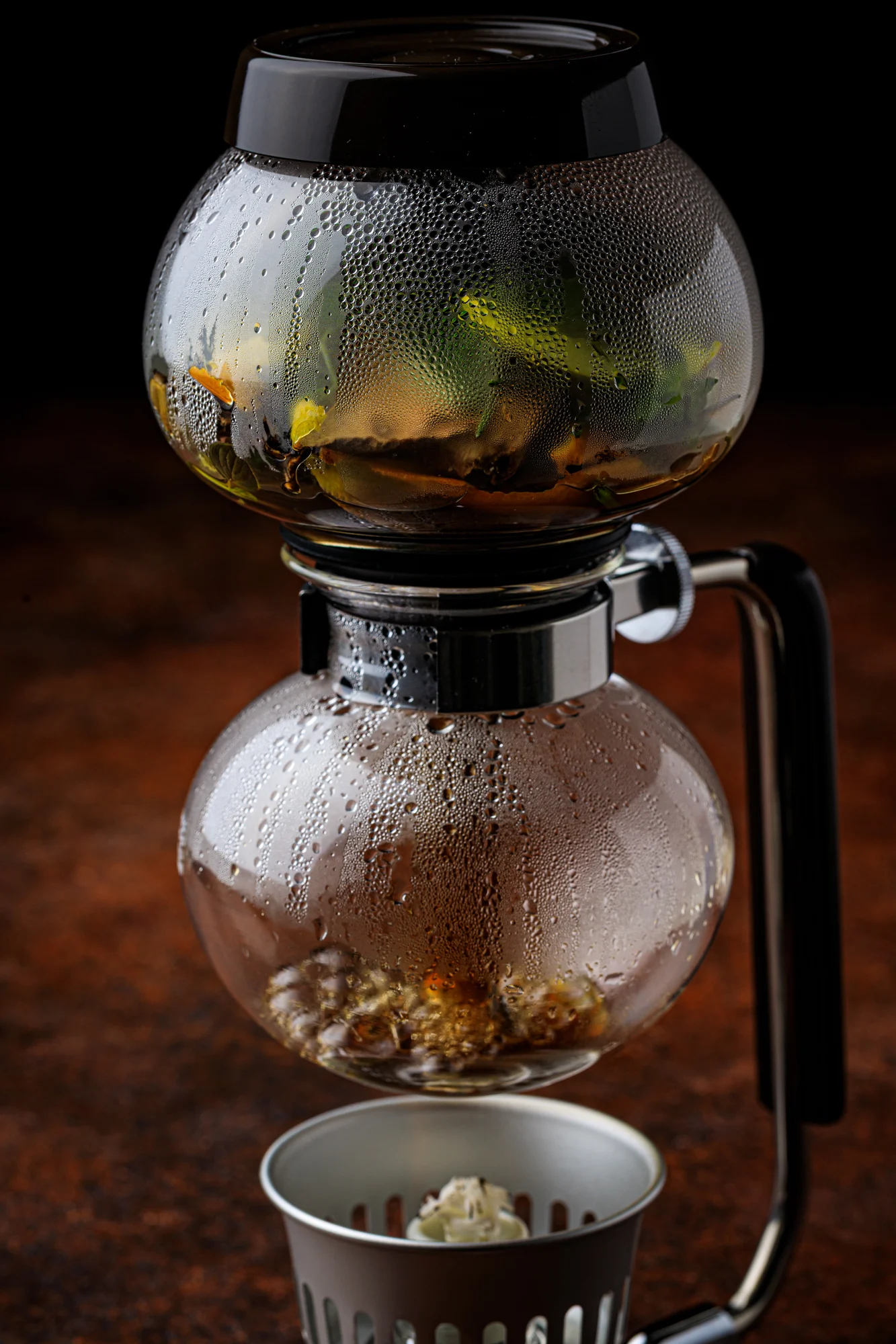 A tableside siphon preparation with ingredients layered in glass vessels.