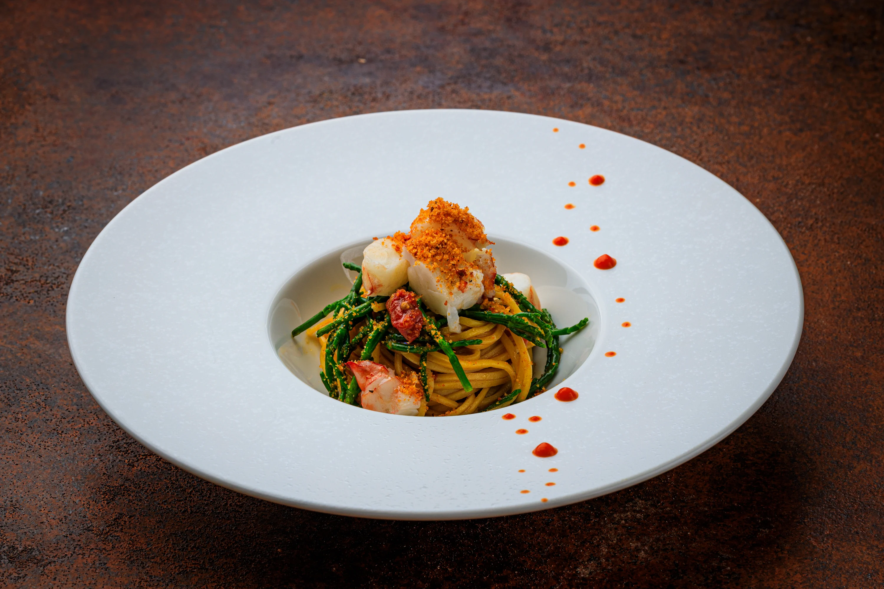 A seafood pasta course with tomato, herbs and delicate red accents.