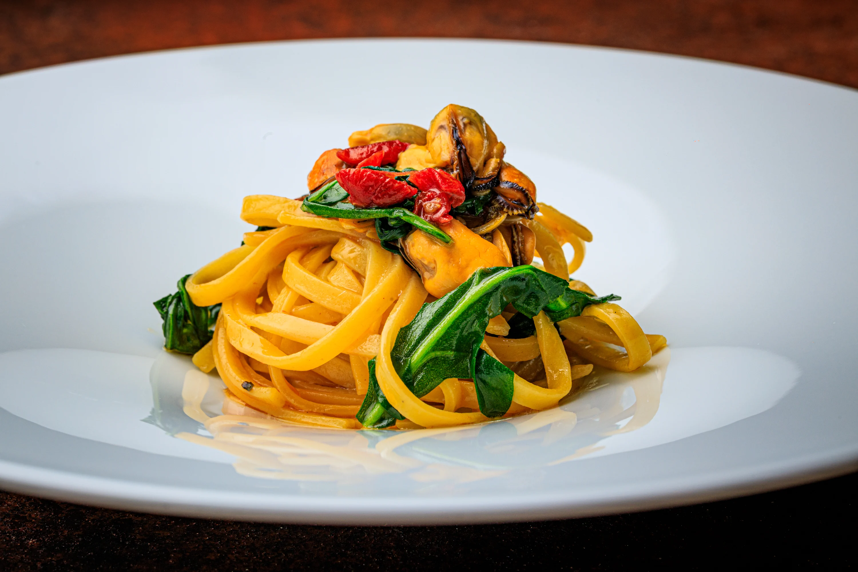 Fresh pasta with mussels, greens and roasted tomatoes.