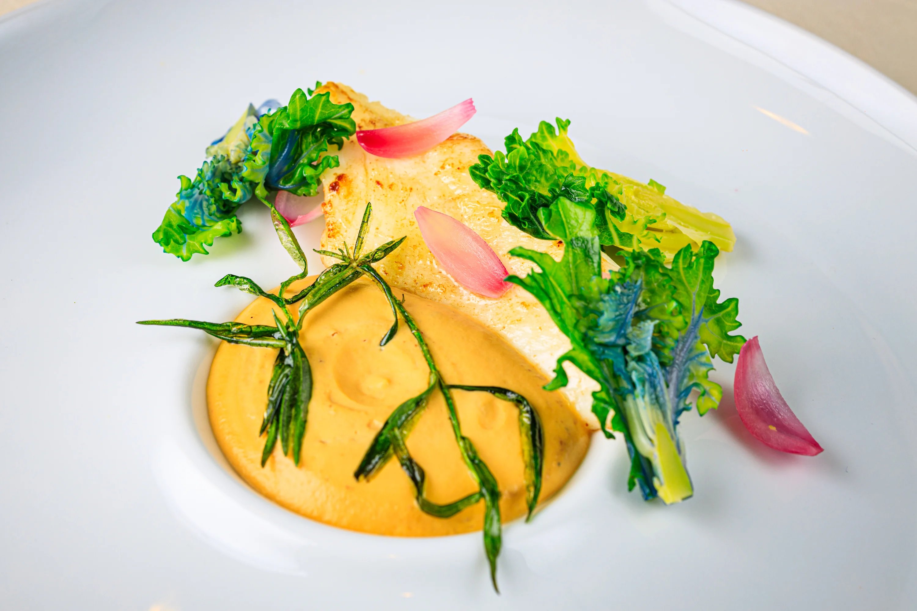 A bright yellow pasta course finished with herbs and vegetables.