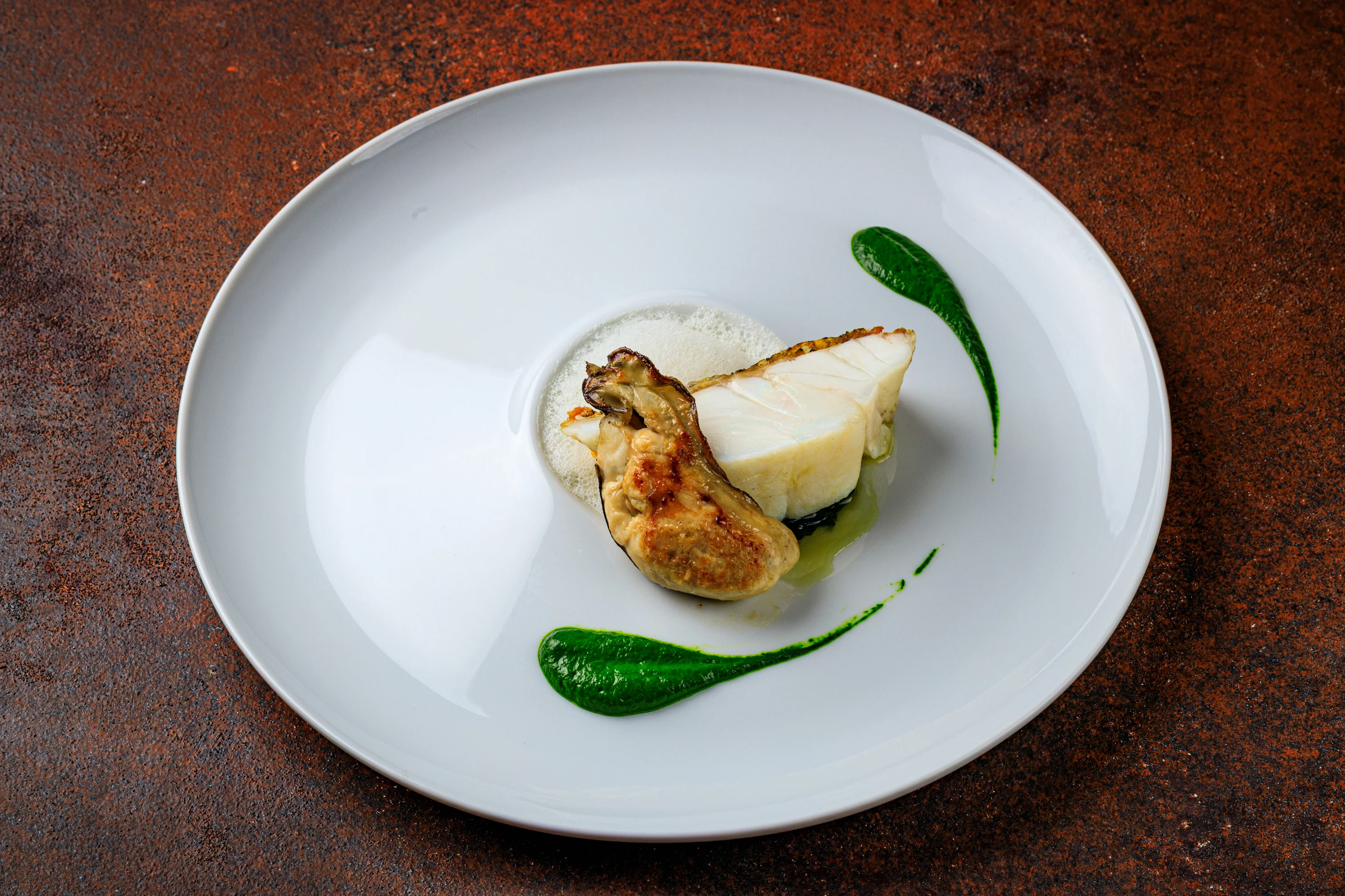 A refined fish course with pale sauce and vivid green accents.