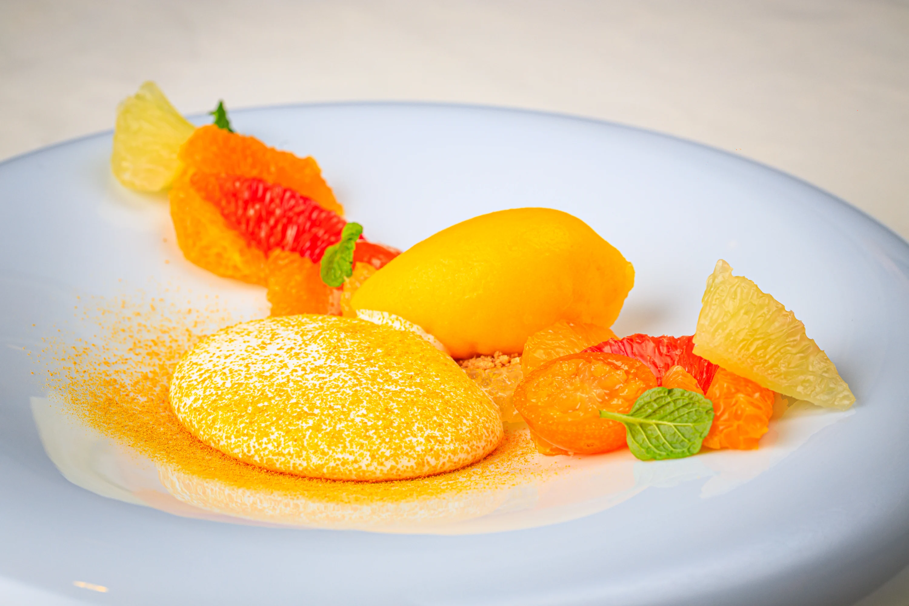 A chef adding the finishing sauce to a plated dessert.