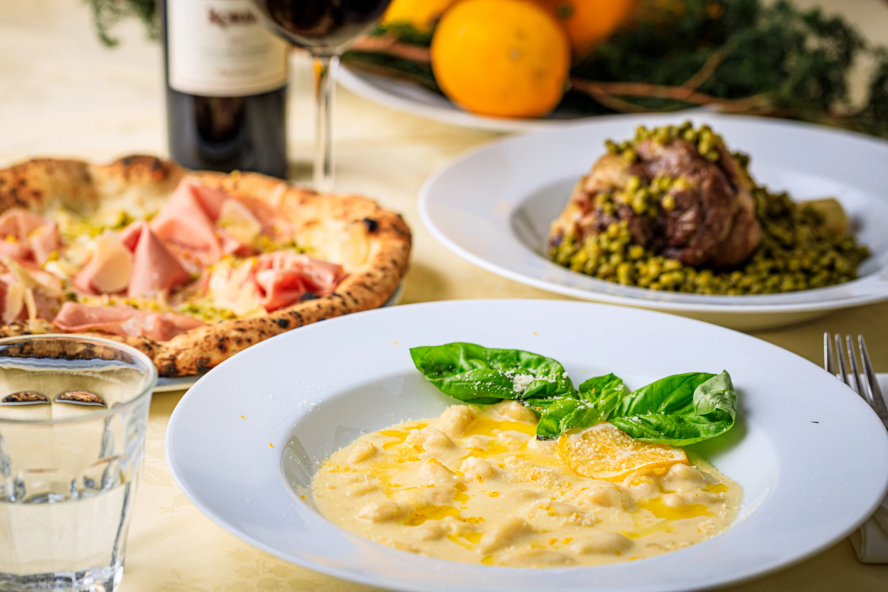 A sliced pizza and baked seafood course served with wine.