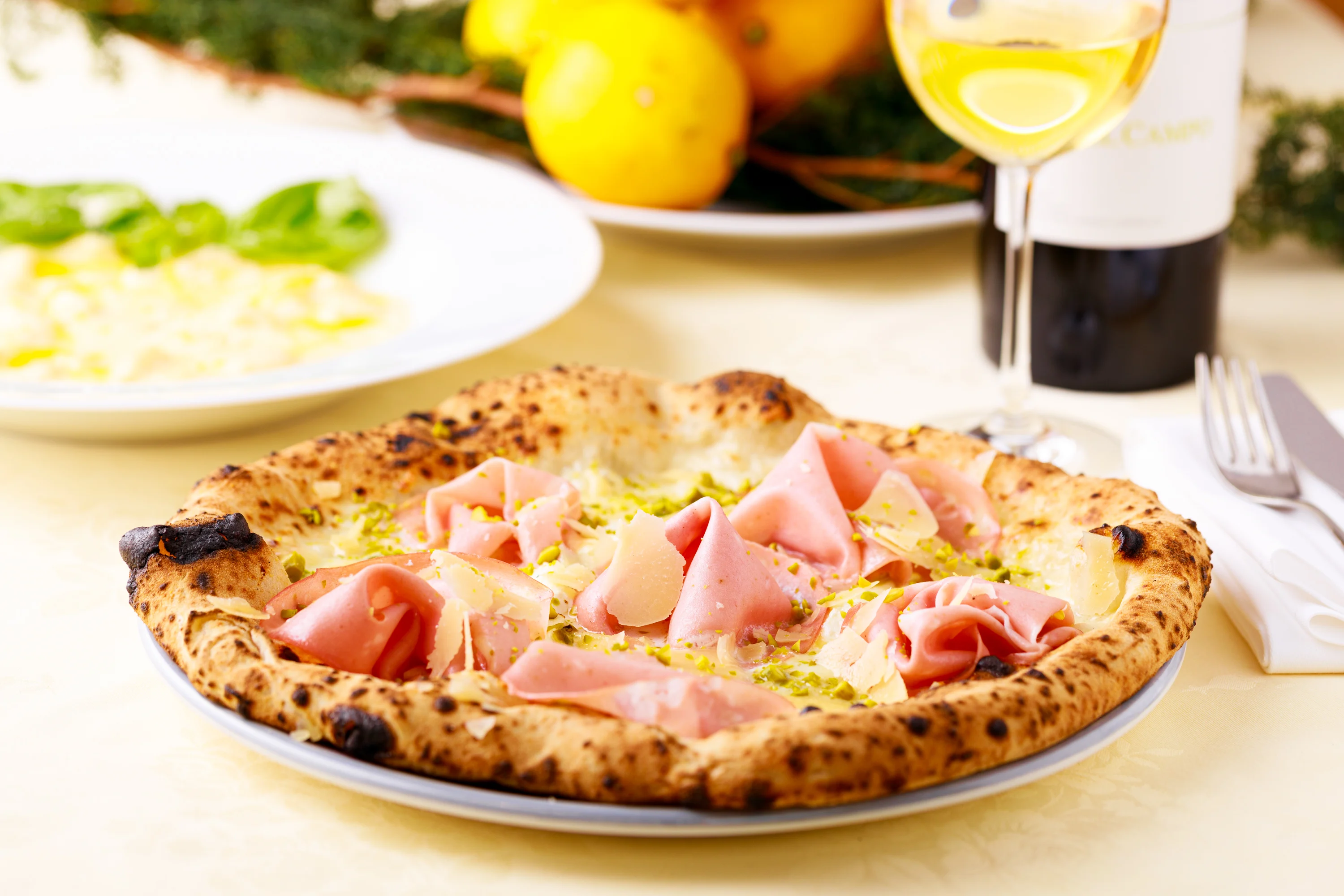 A whole baked fish served with pizza, lemons and white wine.