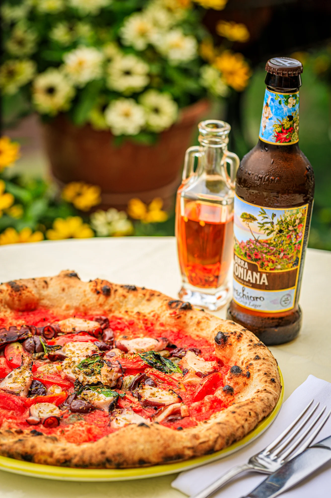 Three pizzas served together with Italian bottled drinks.