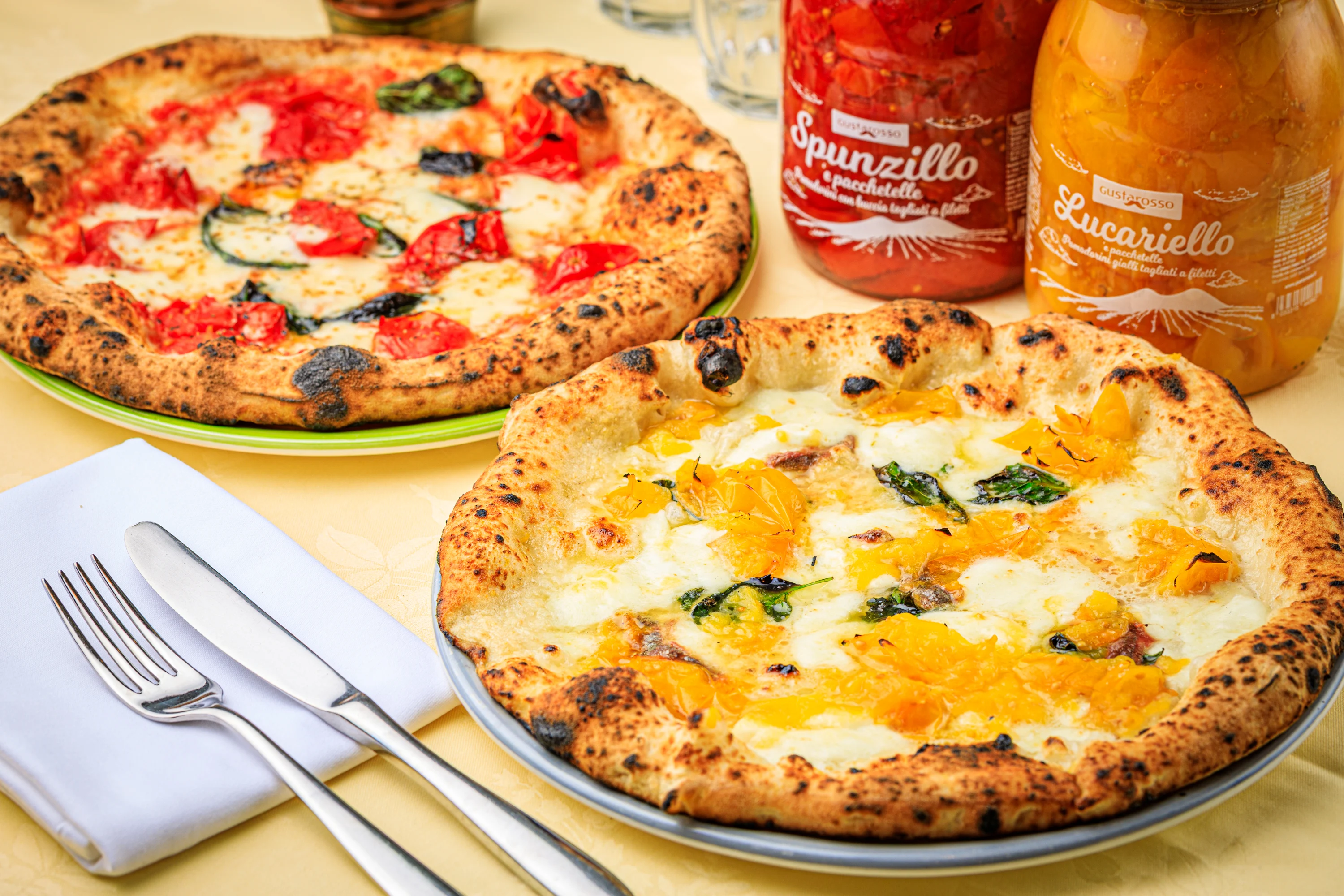 A ham-topped pizza served with an Italian bottled drink.