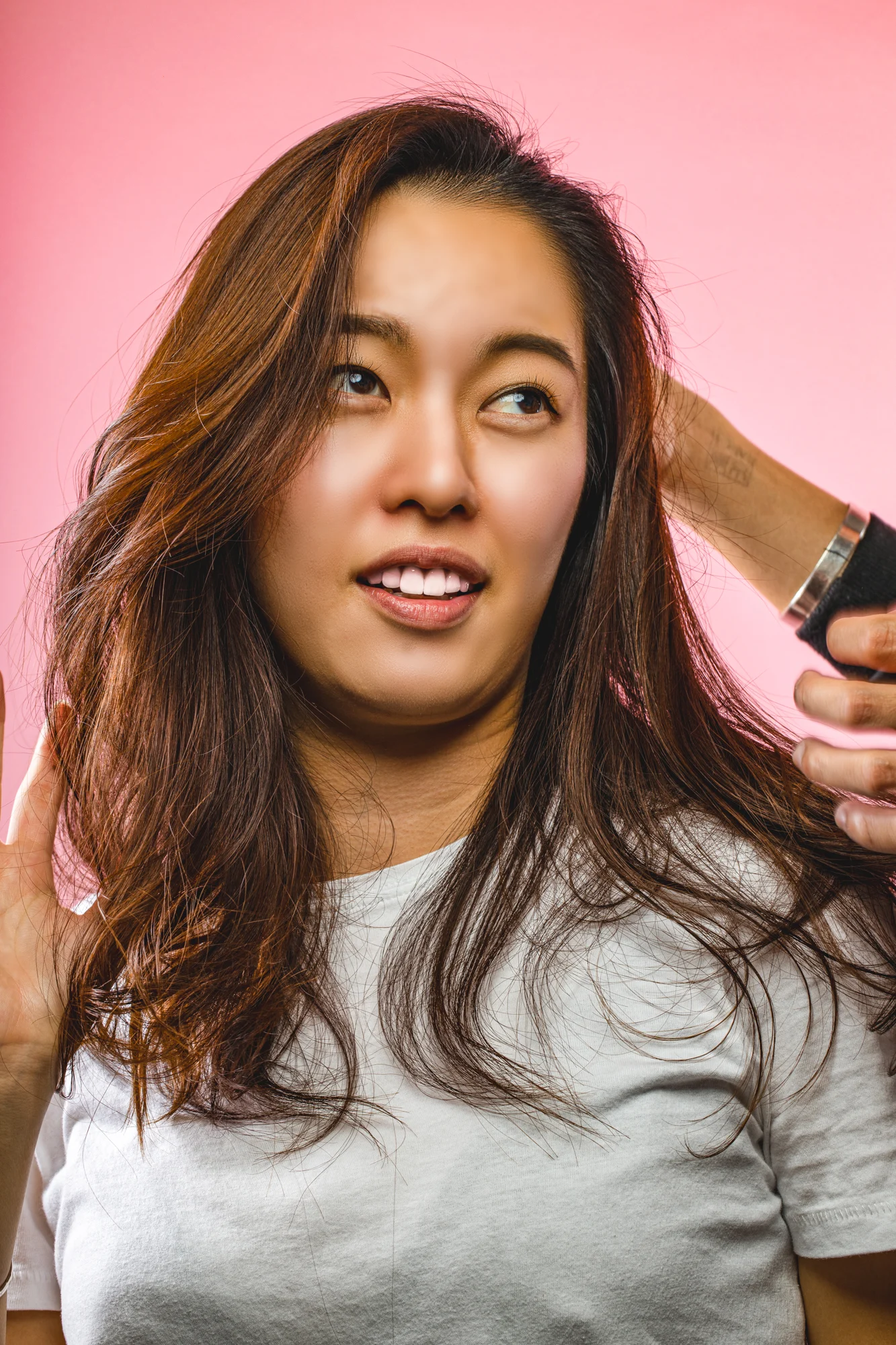 A smiling woman photographed against a soft pink studio background.