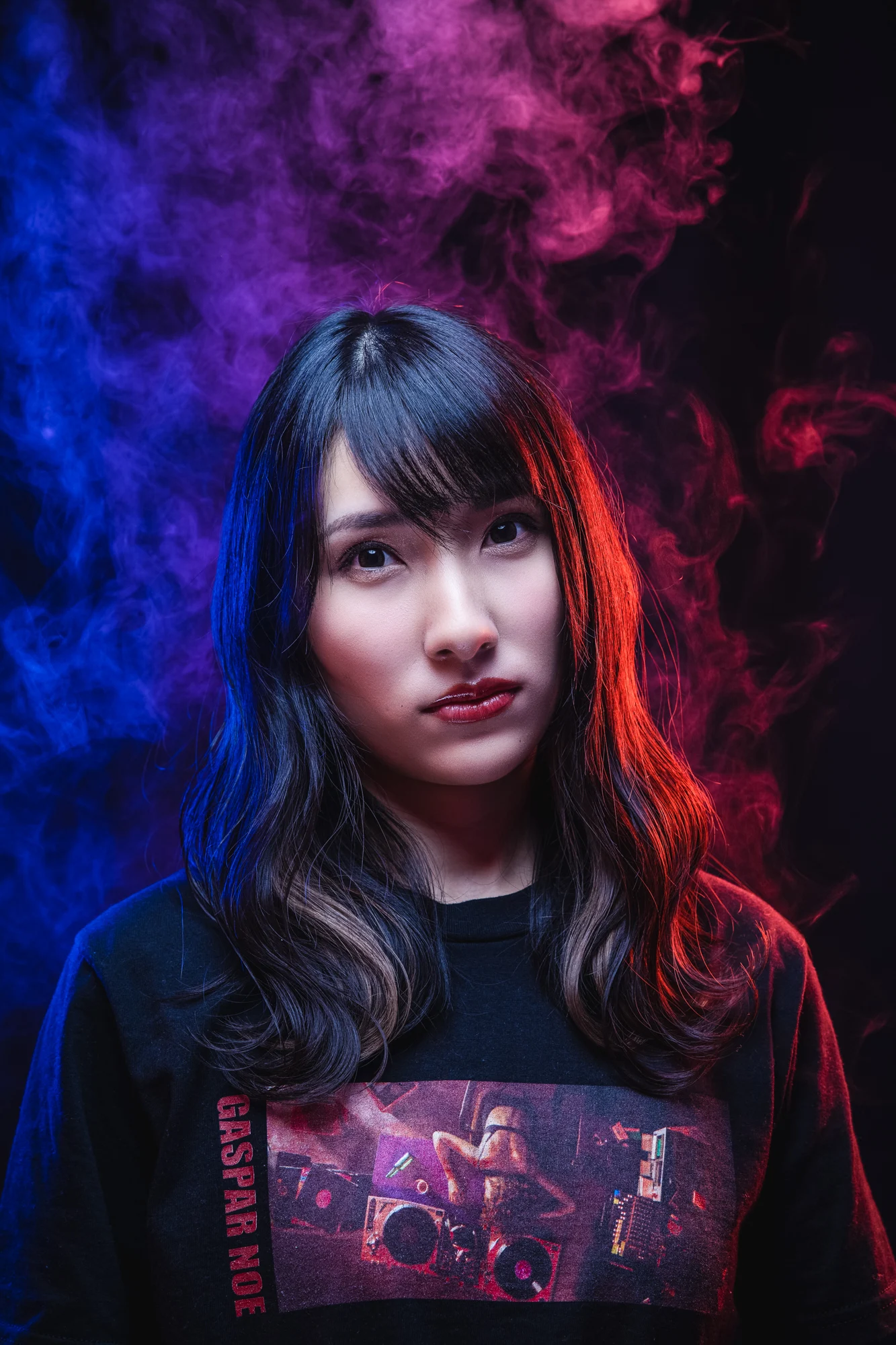 A dramatic portrait of a woman lit through blue and magenta smoke.