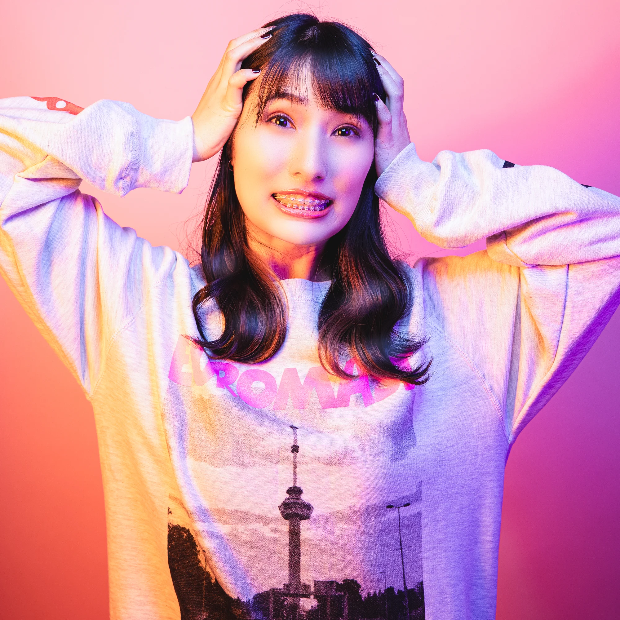 A young woman posing in vivid pink and blue studio light.